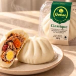 GoBao Classique Vietnamese steamed bun (bánh bao) with salted egg yolk, quail egg and pork sausage, shown cut open beside its package