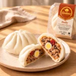 GoBao Daily Vietnamese steamed bun (bánh bao) with quail egg, pork sausage and shiitake mushroom, shown cut open beside its package